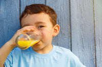 Enfant en train de boire un jus sur fond bleu