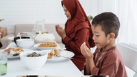 Une maman et son fils à table en train de faire des invocations avant le repas