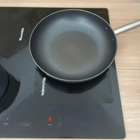 poele posée sur une plaque à induction avec une protection